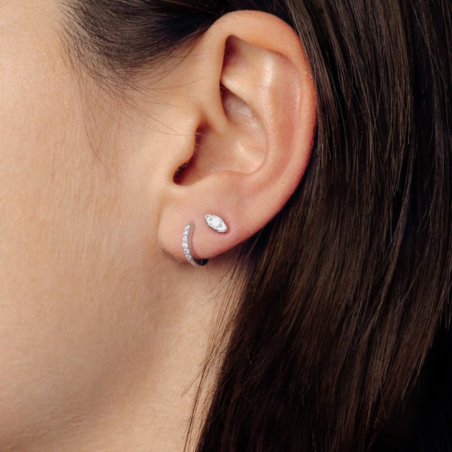 Oreja de mujer con pendiente pequeño en forma de ojo de plata
