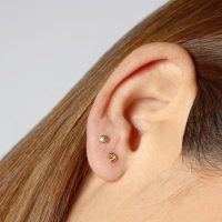 Dos piercings de caracola y concha de mar en una oreja de mujer