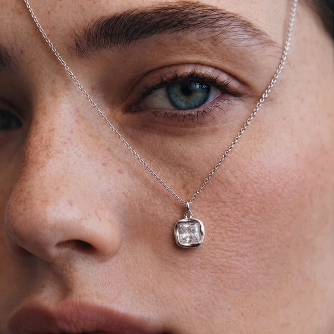 Mujer sujetando colgante de plata con el rostro