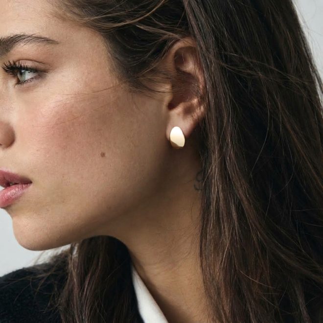Mujer con pendientes pequeños modernos dorados