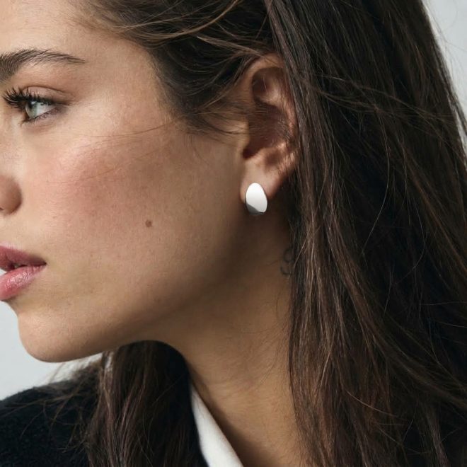 Mujer con pendientes de botón ovalados en plata